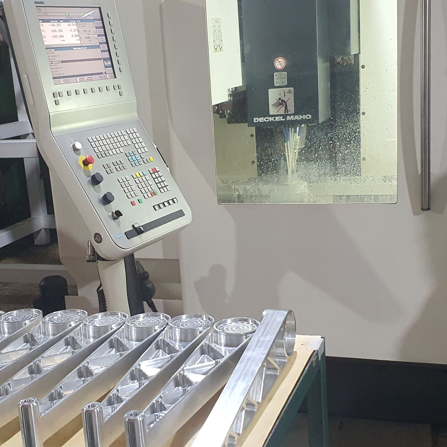 Freshly machined aluminum delta robot arms in front of a CNC machine