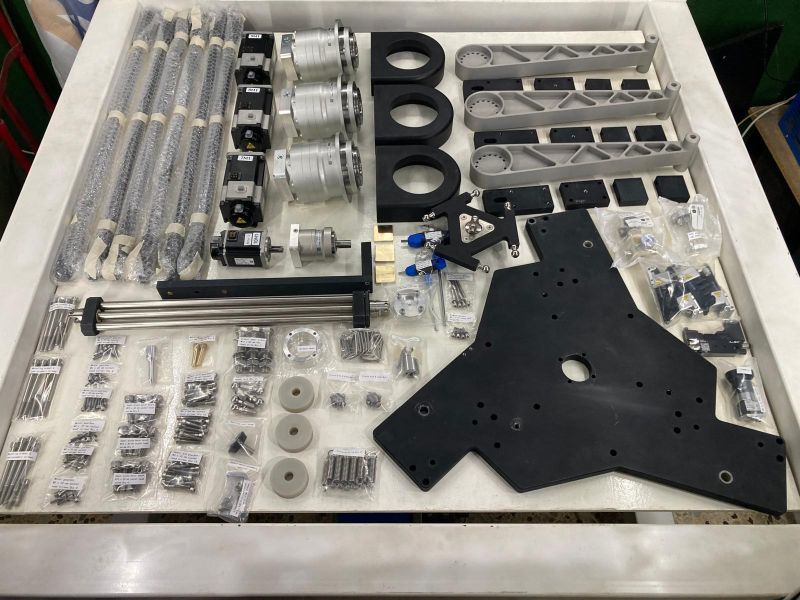 Delta robot kit components laid out in a wooden shipping crate